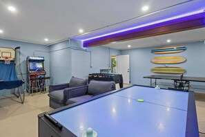 A room with a foosball table, a pool table, and a foosball table with a blue surface. - Coastal Beauty - Canal Front, Dock, Pool, Spa, Game Room by Anna Maria Life Vacation Rentals (Anna Maria)