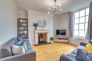 A living room with a fireplace, a television, and a large window. - Spacious 5 -bed Georgian Townhouse I 4 bathrooms I Walk to Liverpool one. (Liverpool)