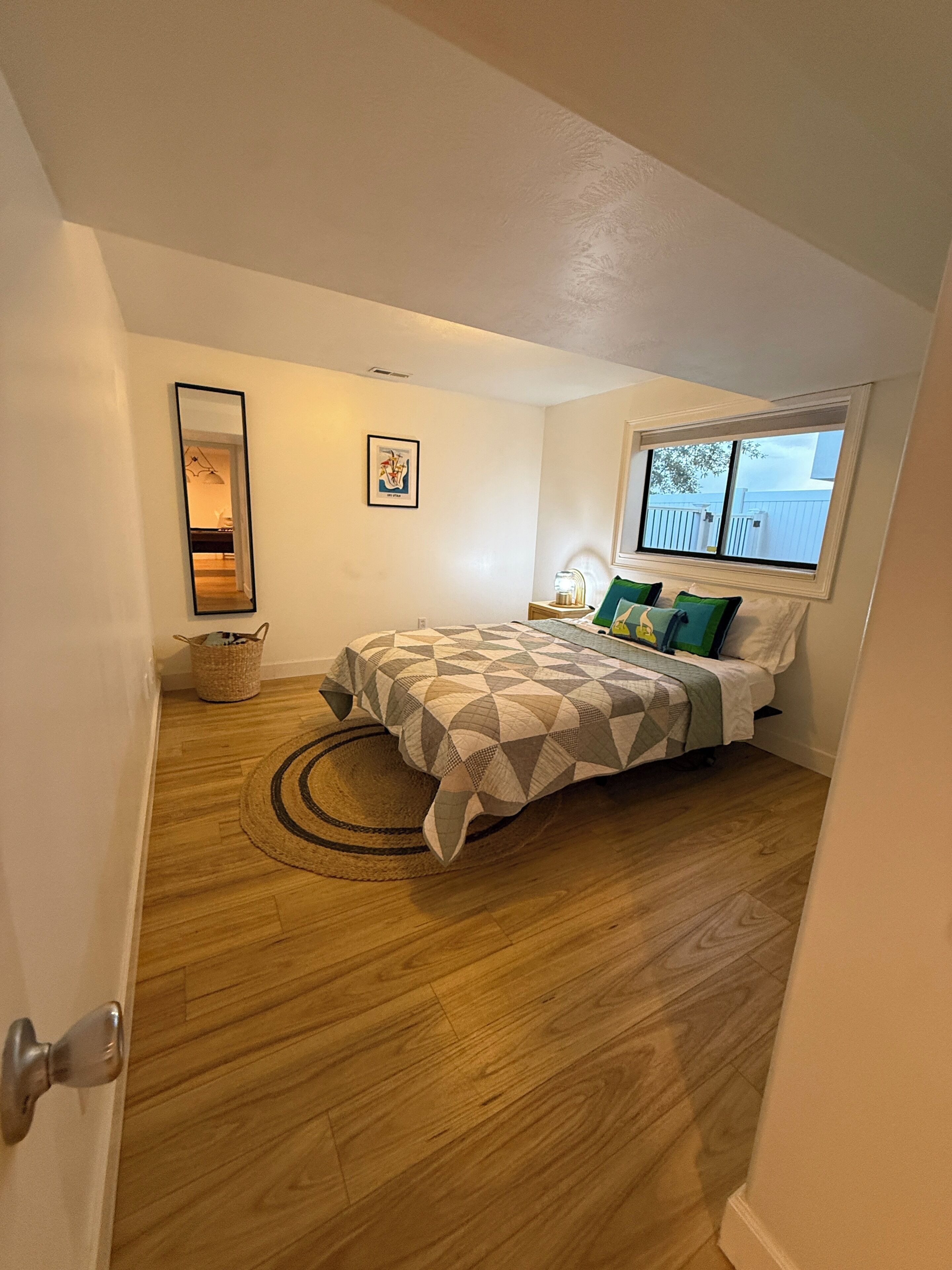 Une chambre à coucher avec un lit, une fenêtre, un miroir et un tapis.