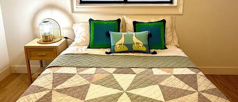 A bedroom with a bed, a window, a bedside table, and a lamp.