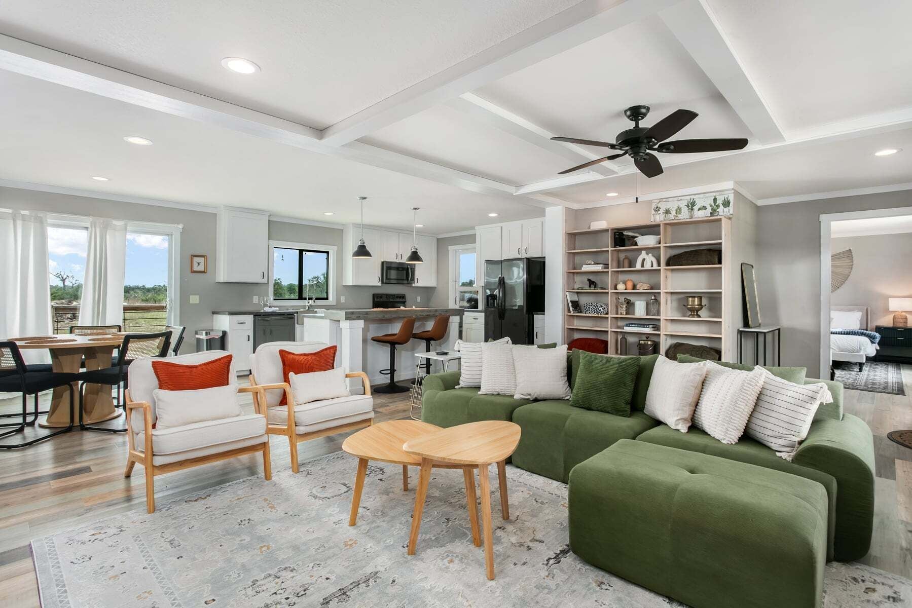 A modern living space with a dining area, kitchen, and a green sofa set.
