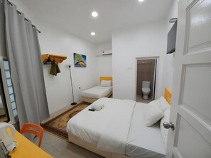 A hotel room with a bed, a chair, a desk, a painting, and a toilet. - The Serai Cottage Transit Hotel (Kuala Terengganu)