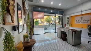 Área de recepção de hotel com piso ladrilhado, balcão de atendimento e placa fixada na parede.