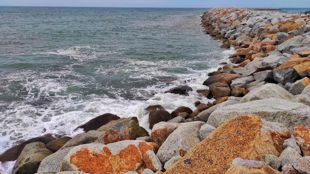 Uma linha costeira rochosa com ondas quebrando nas pedras.