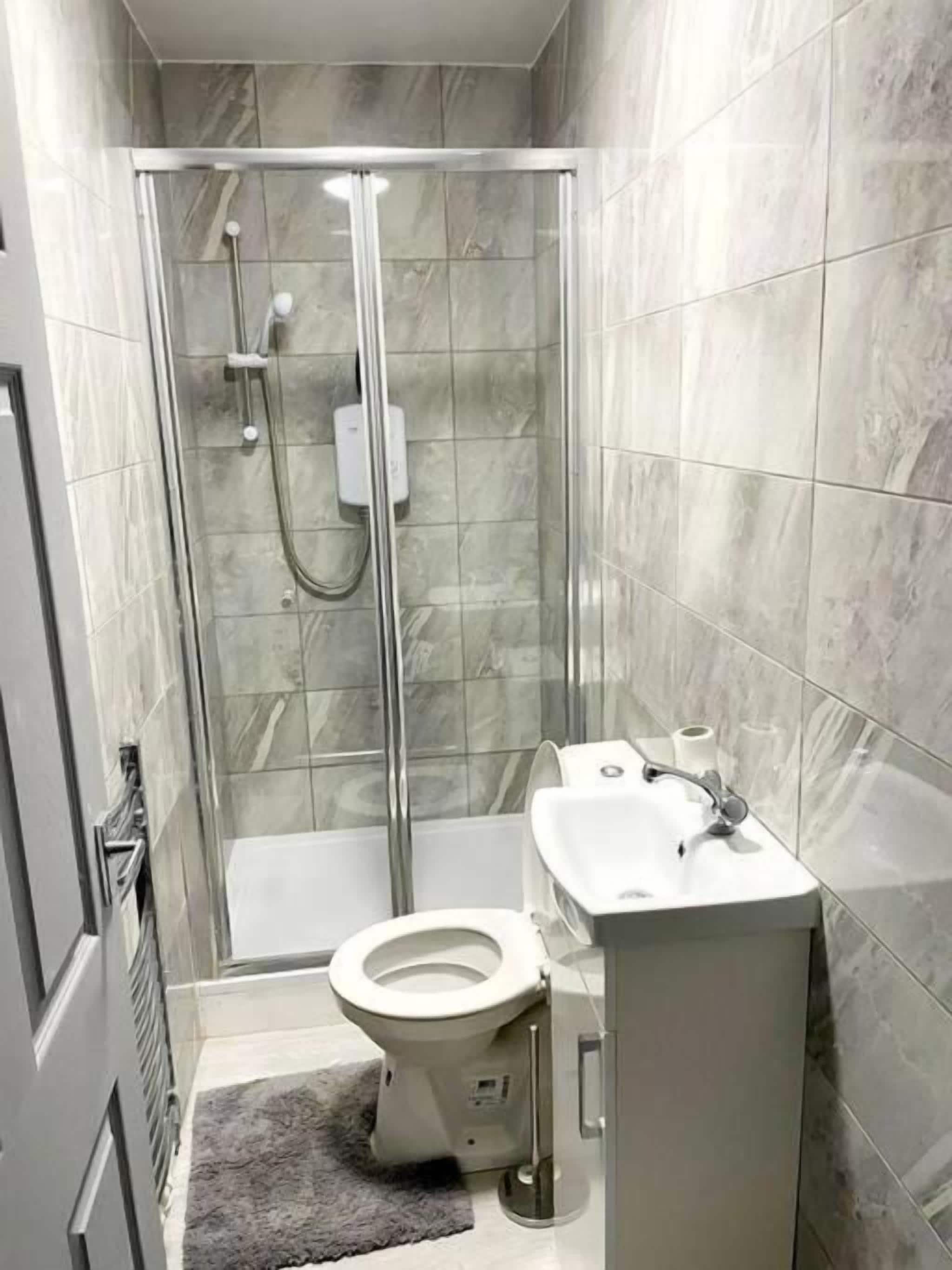 A bathroom with a glass-enclosed shower, a toilet, and a sink.
