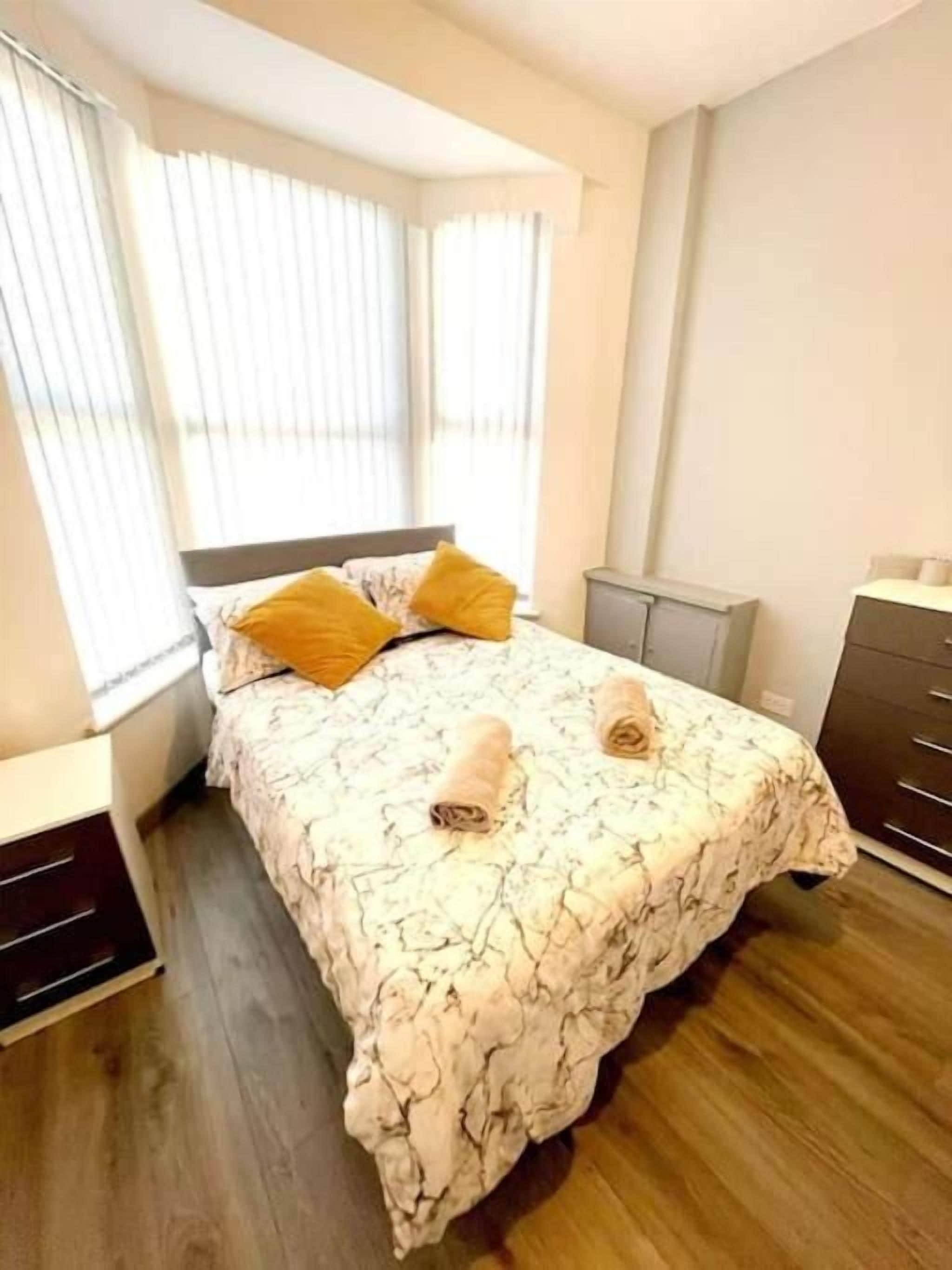 Une chambre à coucher avec un lit, une table de chevet, une commode et une fenêtre avec des stores.