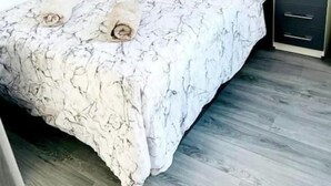 A bed with a marble-patterned bedspread, two pillows, and a nightstand with drawers.