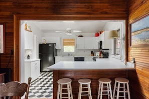 A kitchen with a large island, wooden paneling, and a checkered floor. - The Ark - Add to the History and Memories of Sullivan (Sullivans Island)