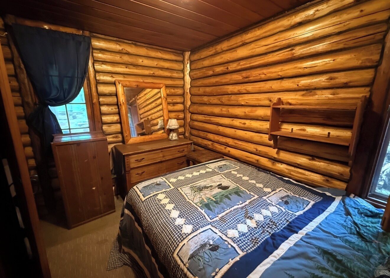 Une chambre de style rustique, avec un lit, une commode et une fenêtre agrémentée de rideaux.