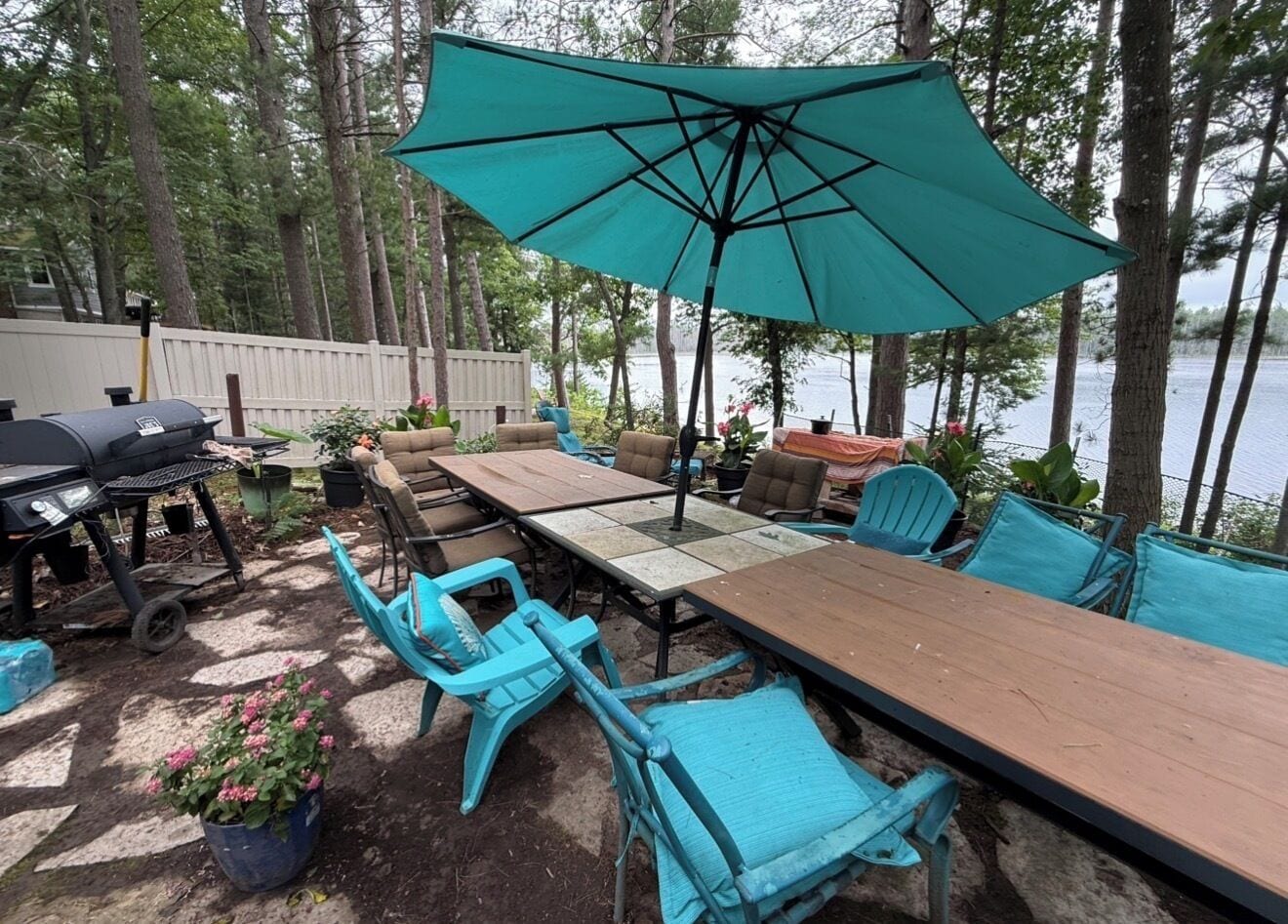 Un espace extérieur aménagé pour les repas, avec une longue table, des chaises et un grand parasol.