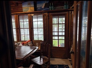 A wooden interior with a dining table and chairs, large windows, and a door leading outside. - GORGEOUS Lakefront Log Home 3-bedrooms tucked into serene woods by Gaylord (Gaylord)