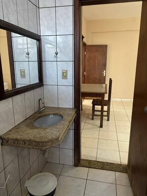A bathroom with a granite sink, a mirror, a toilet, and a wooden cabinet. - Hotel Via Montes (Montes Claros)