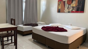 Ein Hotelzimmer mit zwei Betten, einem Esstisch, einem Stuhl und einem Bild an der Wand.