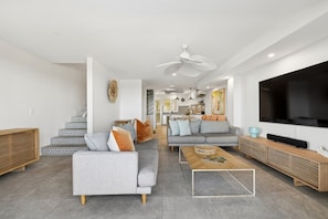 Un salon moderne avec un canapé gris, une table basse et un téléviseur.