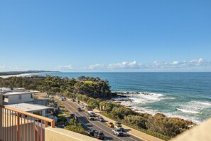 A coastal road with vehicles, a beach, and a clear sky. - Azure Dreaming - Beachfront Villa @ Coolum Beach (Coolum Beach)