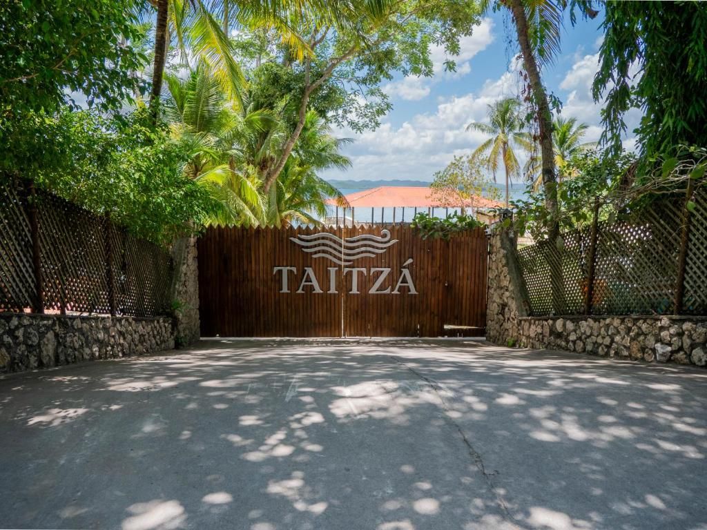 A gated entrance with a wooden gate and the name 'TAITZA' prominently displayed.