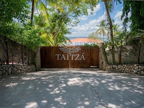 A gated entrance with a wooden gate and the name 'TAITZA' prominently displayed.