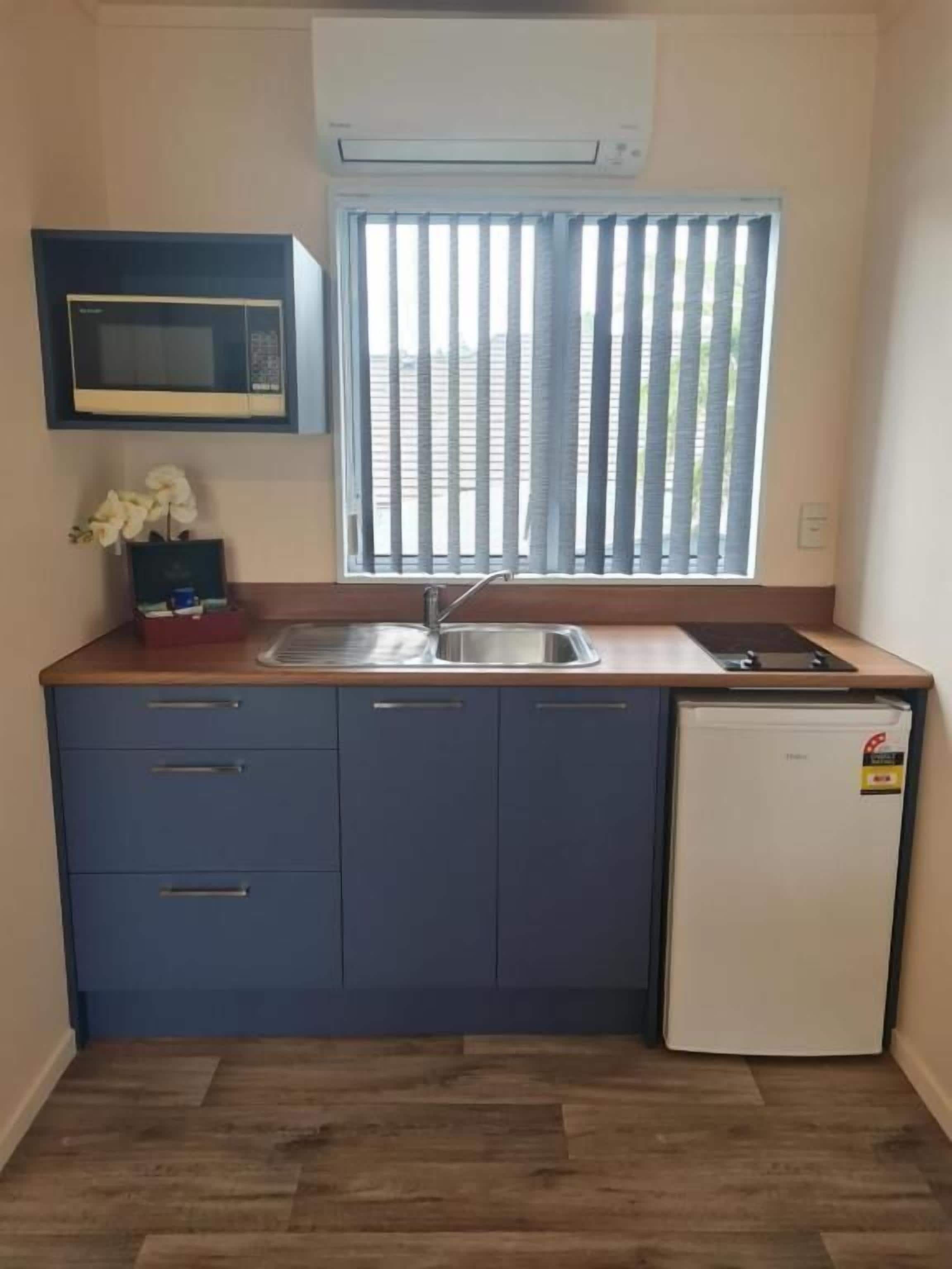 A compact kitchen with a microwave, sink, and refrigerator.