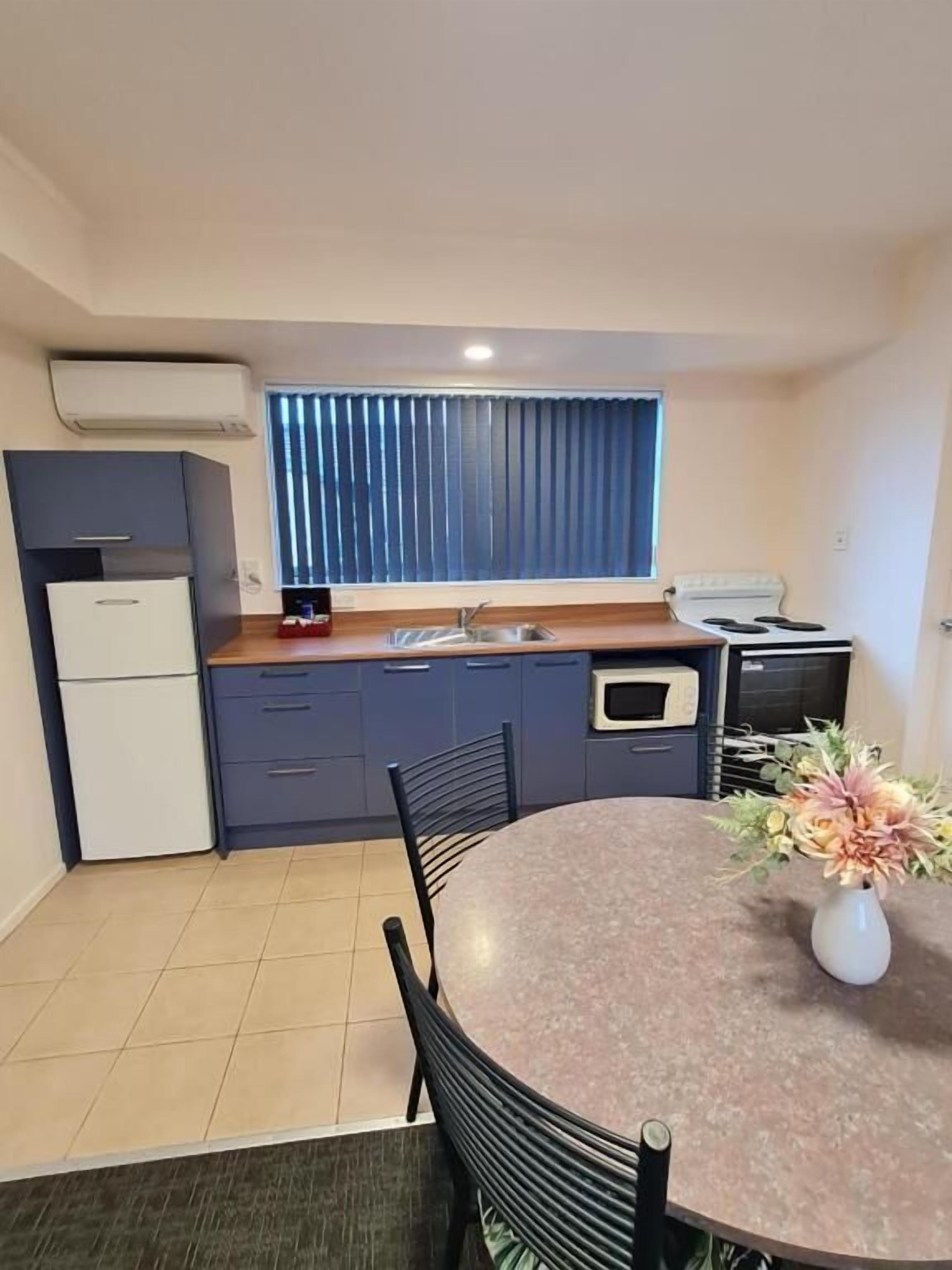 A compact kitchen with a dining area, a built-in oven, and a window with blinds.