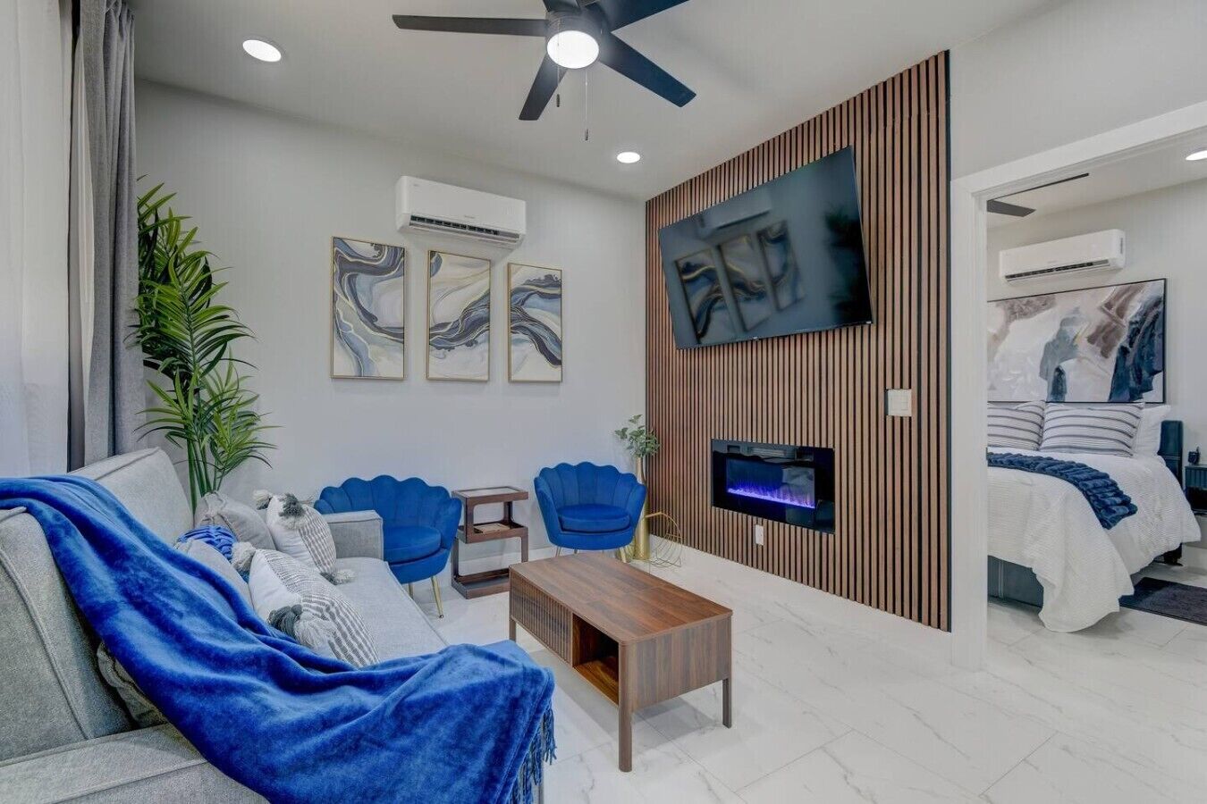 Una sala de estar moderna con un sofá, sillones, una mesa de centro, un televisor y una chimenea.