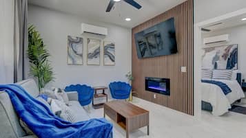 Una sala de estar moderna con un sofá, sillones, una mesa de centro, un televisor y una chimenea.