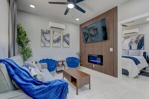 Un salon moderne avec un canapé, des fauteuils, une table basse, un téléviseur et une cheminée.