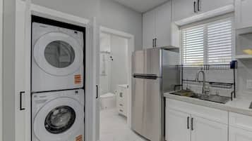 Una cocina moderna con un refrigerador de acero inoxidable, una lavadora integrada y un lavabo con escurreplatos.