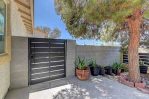 A gated entrance with a metal gate, potted plants, and a tree.