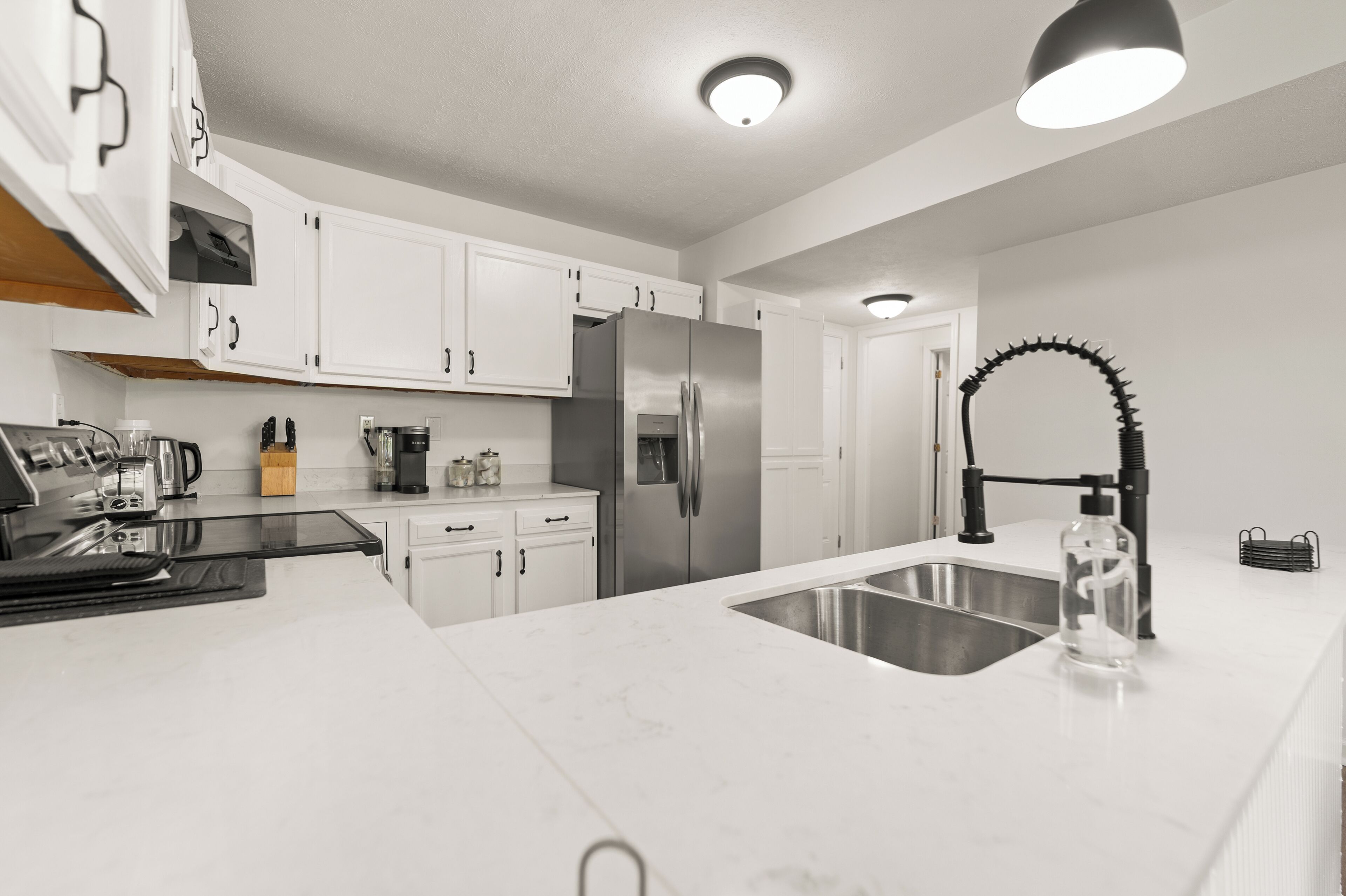 A modern kitchen with white cabinets, stainless steel appliances, and a black faucet.