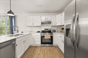 Eine moderne Küche mit weißen Schränken, Edelstahlgeräten und Holzboden.