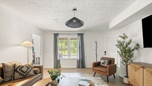 Ein modernes Wohnzimmer mit Sofa, Sessel, Couchtisch und einer Topfpflanze.
