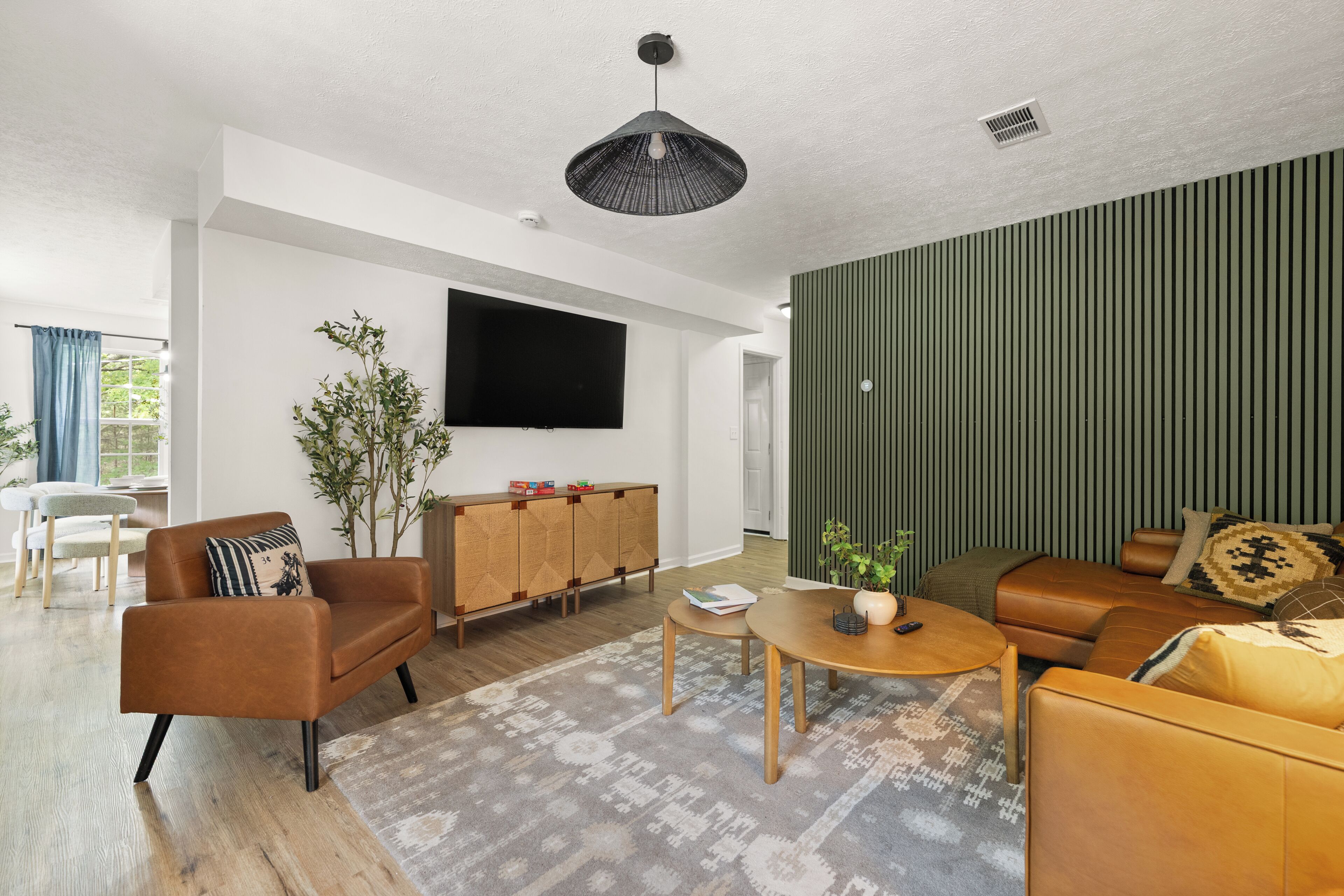 A modern living room with a flat-screen TV, leather sofas, a coffee table, and a patterned rug.