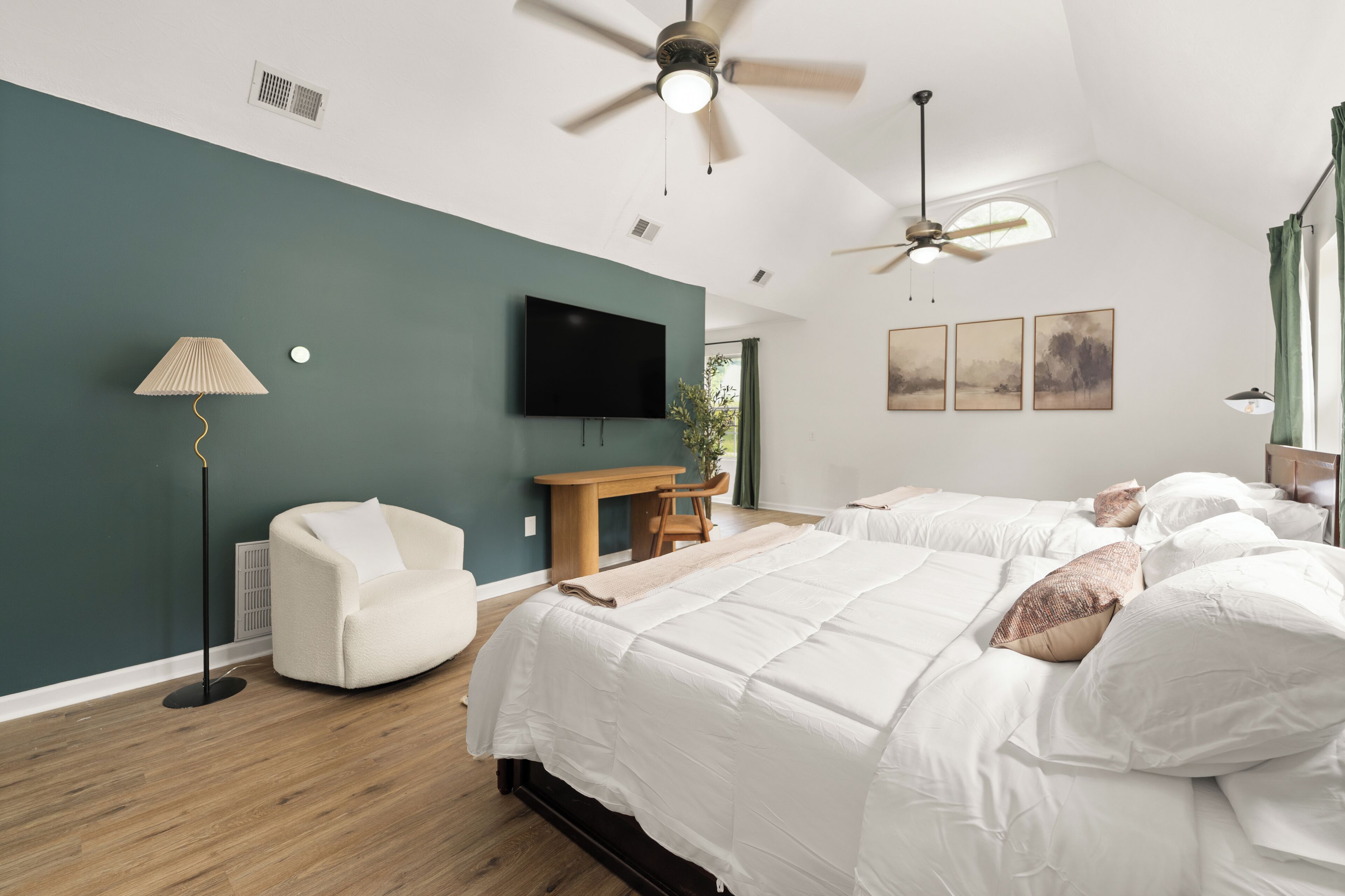 A hotel room with two beds, a ceiling fan, a flat-screen TV, a desk, and a chair.