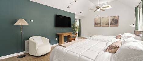 A hotel room with two beds, a ceiling fan, a flat-screen TV, a desk, and a chair.