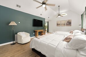 A hotel room with two beds, a ceiling fan, a flat-screen TV, a desk, and a chair.