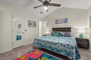 A bedroom with a bed, a nightstand, a lamp, a ceiling fan, and a door. - Guava Ohana 17105-Beach Nearby-Sleeps 11 (Panama City Beach)