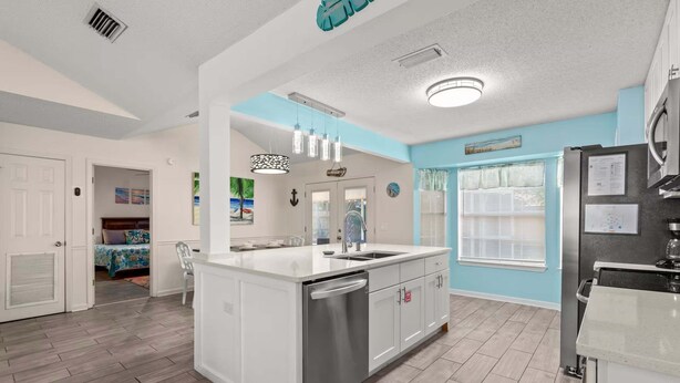 A modern kitchen with a central island, a built-in dishwasher, and a refrigerator. - Guava Ohana 17105-Beach Nearby-Sleeps 11 (Panama City Beach)
