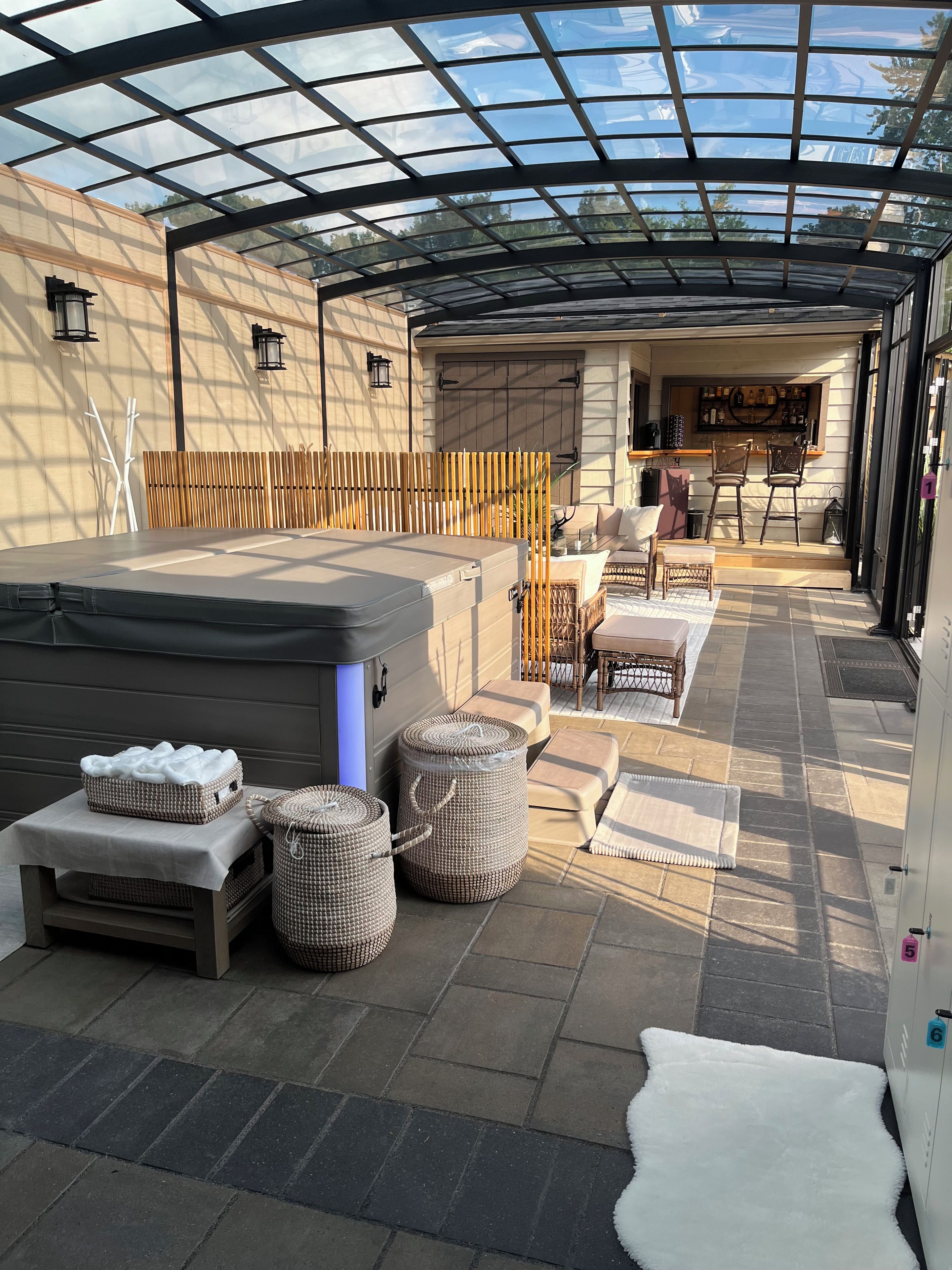 Un espace extérieur abrité comprenant un jacuzzi, des sièges et un bar.