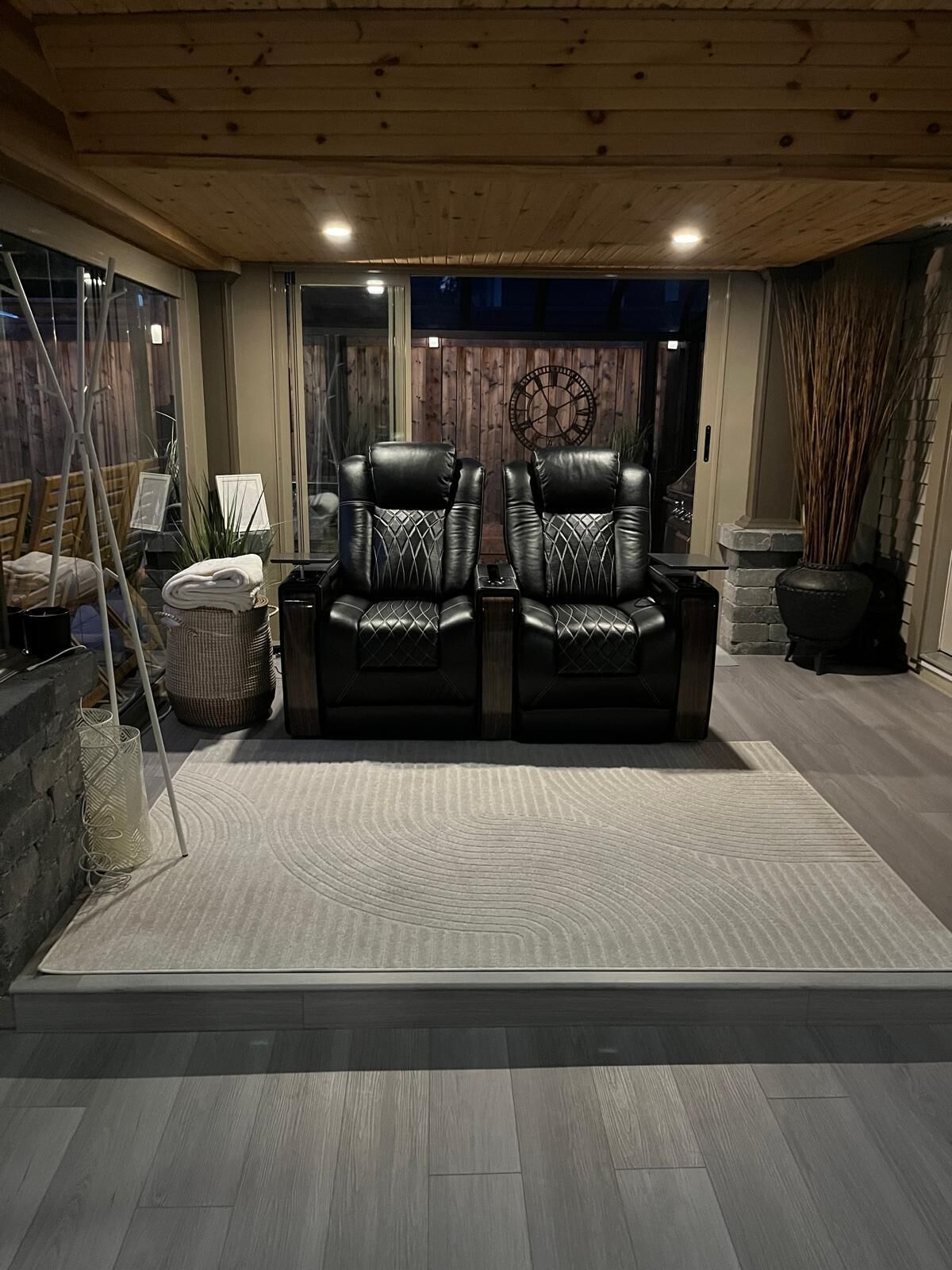 A room with two leather recliners, a wooden ceiling, and a large window.