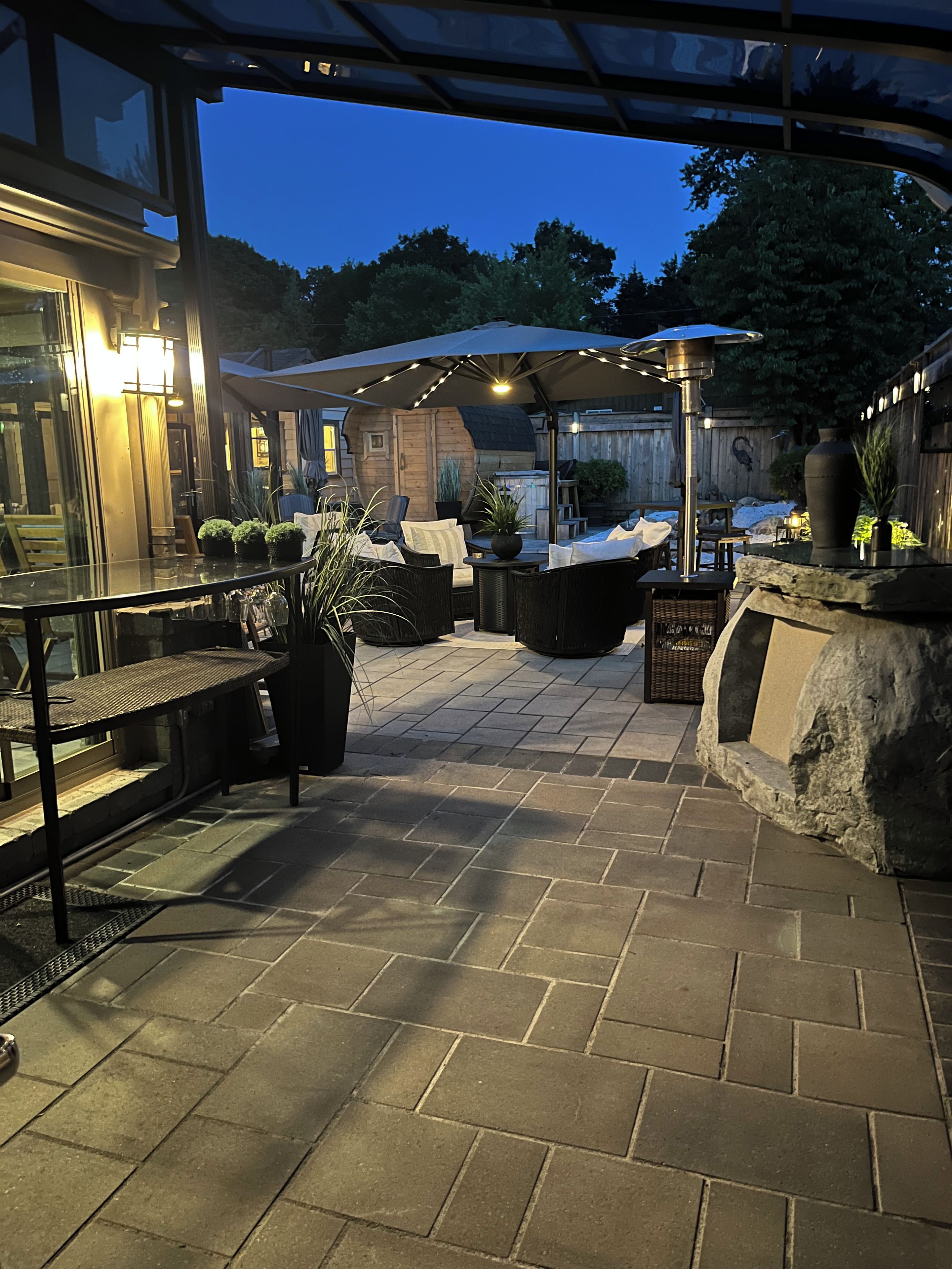 An outdoor patio area with stone flooring, outdoor furniture, and potted plants.