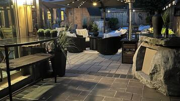 An outdoor patio area with stone flooring, outdoor furniture, and potted plants.
