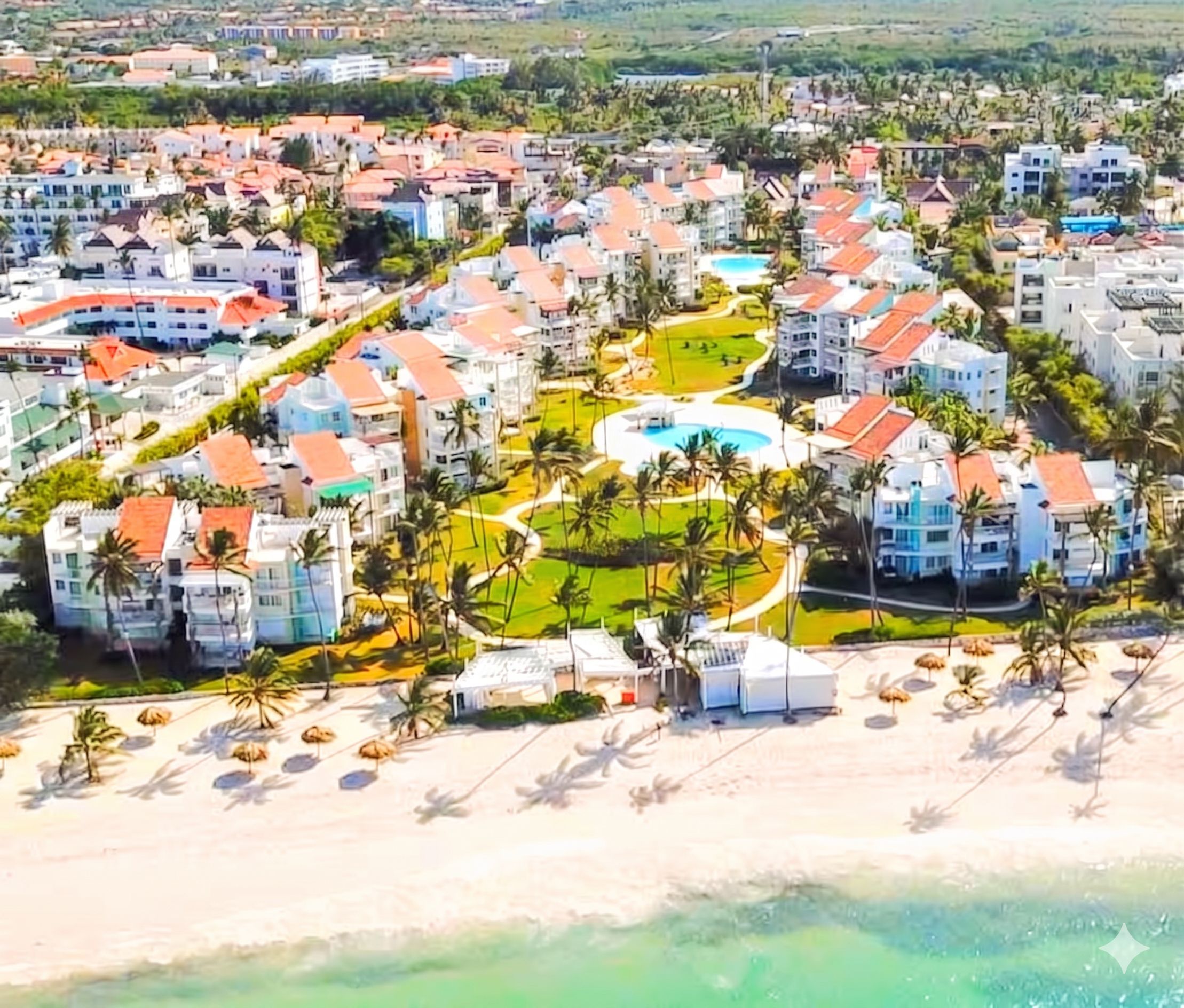 Een resort met meerdere gebouwen, een centraal zwembad en een strand.