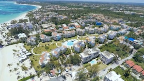 Ein Resort mit mehreren Gebäuden, einem zentralen Pool und einem Strand.