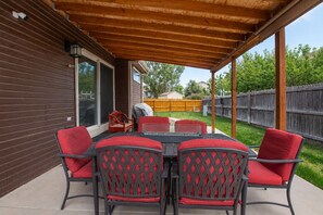 An outdoor patio with a wooden pergola, a table with chairs, and a barbecue grill. - 3BR Home w/ Private Cinema • BBQ • Home Office • 10 minutes from Airport (Denver)