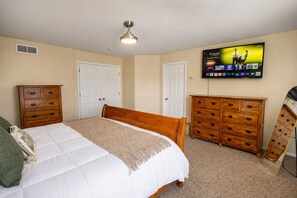 A bedroom with a bed, two dressers, a ceiling fan, and a TV mounted on the wall. - 3BR Home w/ Private Cinema • BBQ • Home Office • 10 minutes from Airport (Denver)