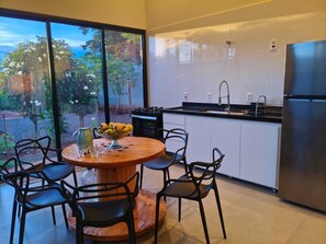 Une cuisine moderne dotée d’une grande fenêtre, d’une table à manger avec des chaises et d’un réfrigérateur.