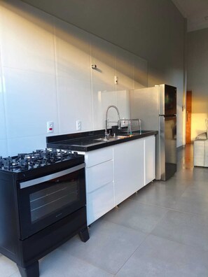 A modern kitchen with a gas stove, stainless steel appliances, and white cabinetry.