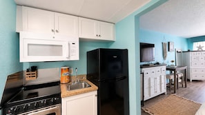 A compact kitchen with a microwave, stove, refrigerator, and a sink. - Endless Ocean Views | 15th Floor King Studio (Myrtle Beach)