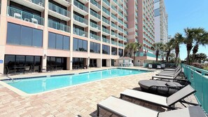A hotel with a swimming pool, outdoor seating, and a multi-story building with balconies. - Endless Ocean Views | 15th Floor King Studio (Myrtle Beach)