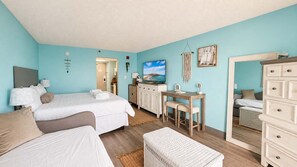 A room with a bed, a desk, a dresser, and a mirror. - Endless Ocean Views | 15th Floor King Studio (Myrtle Beach)